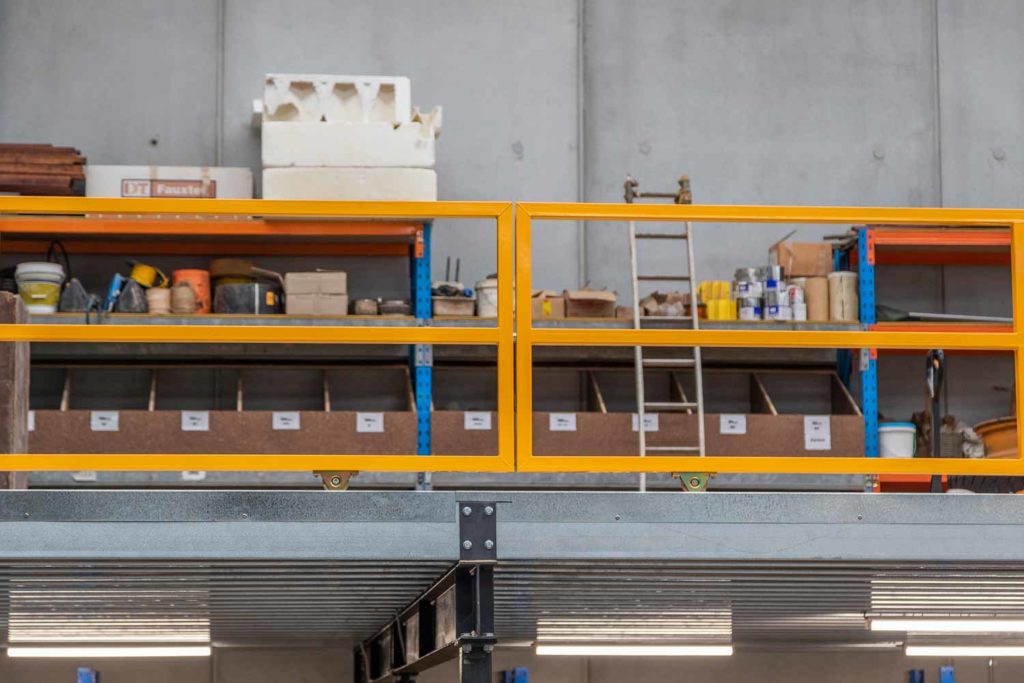 Close-up view of yellow mezzanine safety gate with racking and materials stored in industrial warehouse