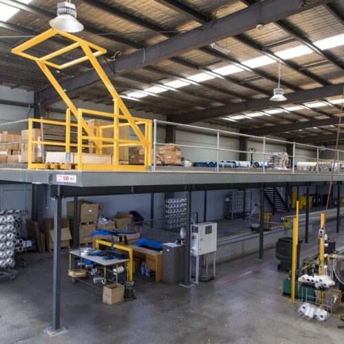 Installed modular mezzanine with integrated yellow safety gate in an operational warehouse setting