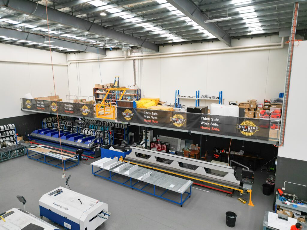 Industrial mezzanine storage platform above metal coil racks, maximising warehouse space and efficiency.