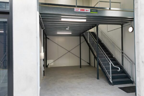 Structural mezzanine floor showing steel staircase and safety balustrade installation.
