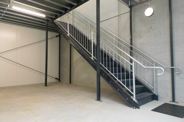 Structural steel mezzanine floor with integrated safety handrails for industrial storage.